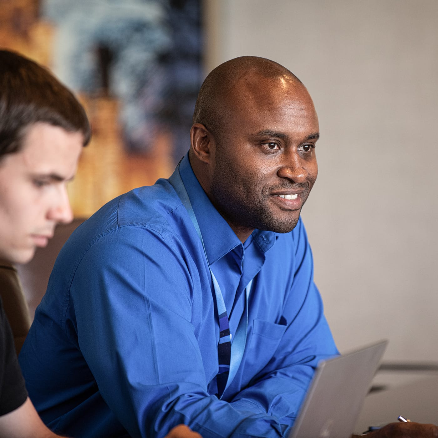 A man looking at a computer screen and another man smiling into the distance.